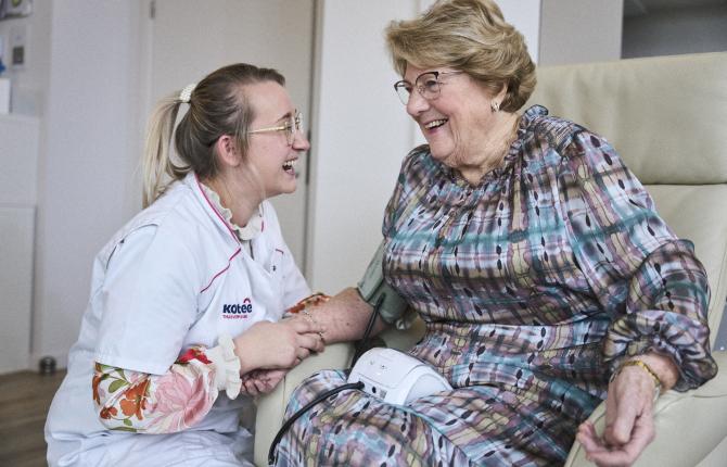 verzorgende slaat babbeltje met oudere dame