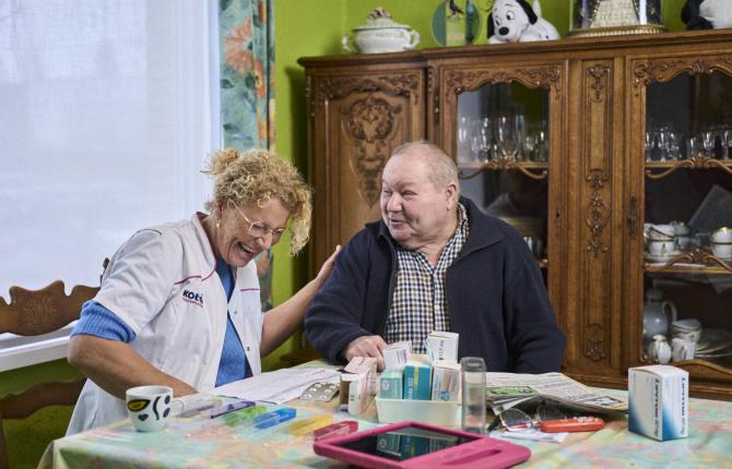 verzorgende en cliënt lezen samen de krant